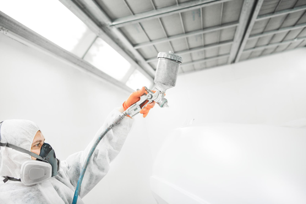 homme qui met de la peinture sur une voiture