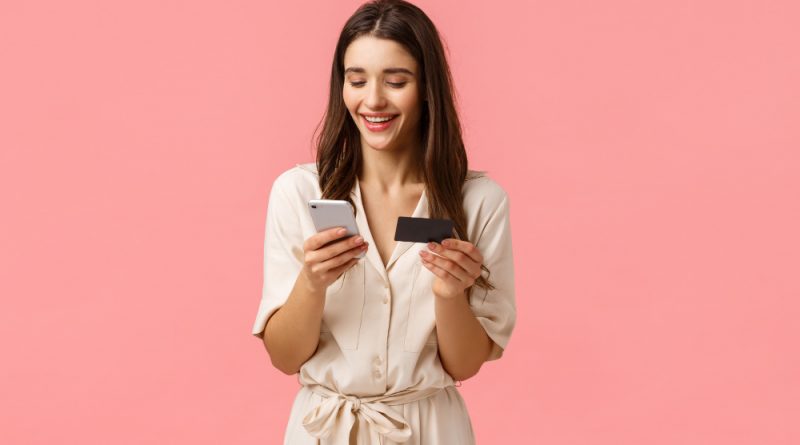 femme sur son telephone avec une carte de crédit