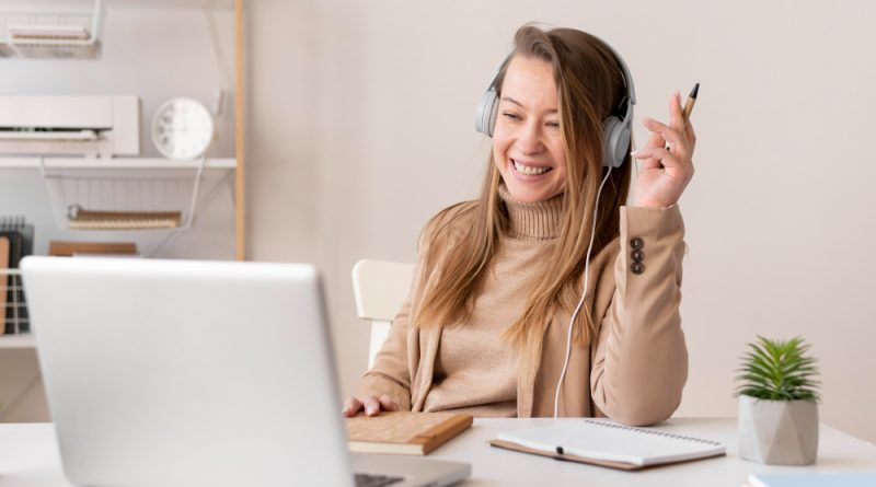 une jeune femme suivant une formation en ligne en rigolant devant son ordinateur