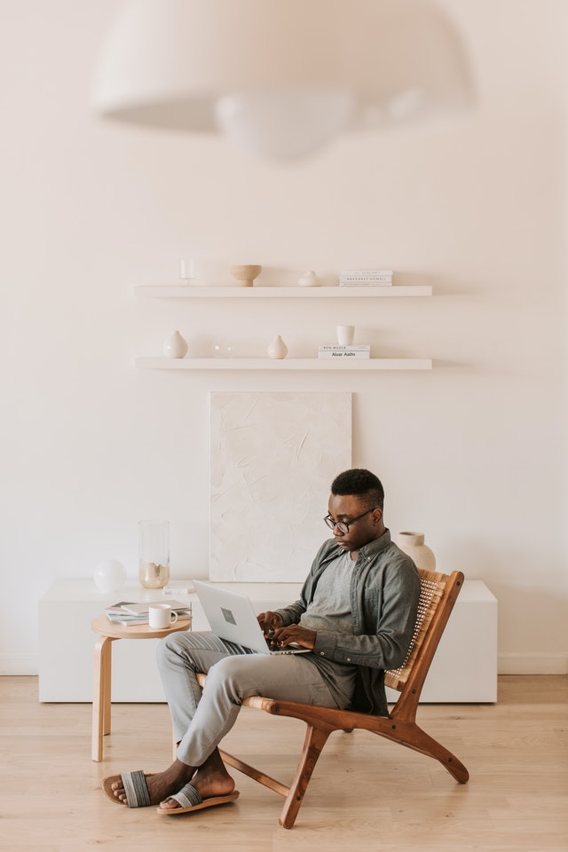 Un homme assis sur une chaise et tenant son ordinateur portable.