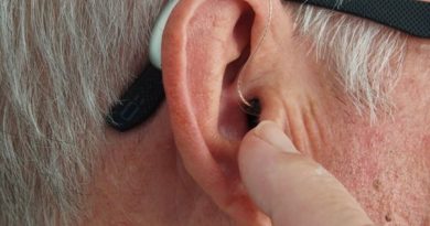 Homme touchant son appareil auditif inséré dans son oreille