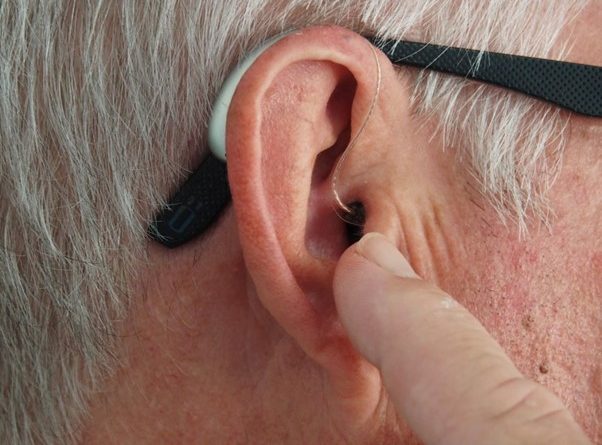Homme touchant son appareil auditif inséré dans son oreille