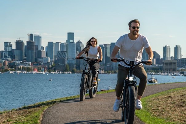 Un homme et une femme faisant du vélo électrique au bord d'une rivière