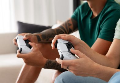 deux personnes assises sur le canapé jouant à la console