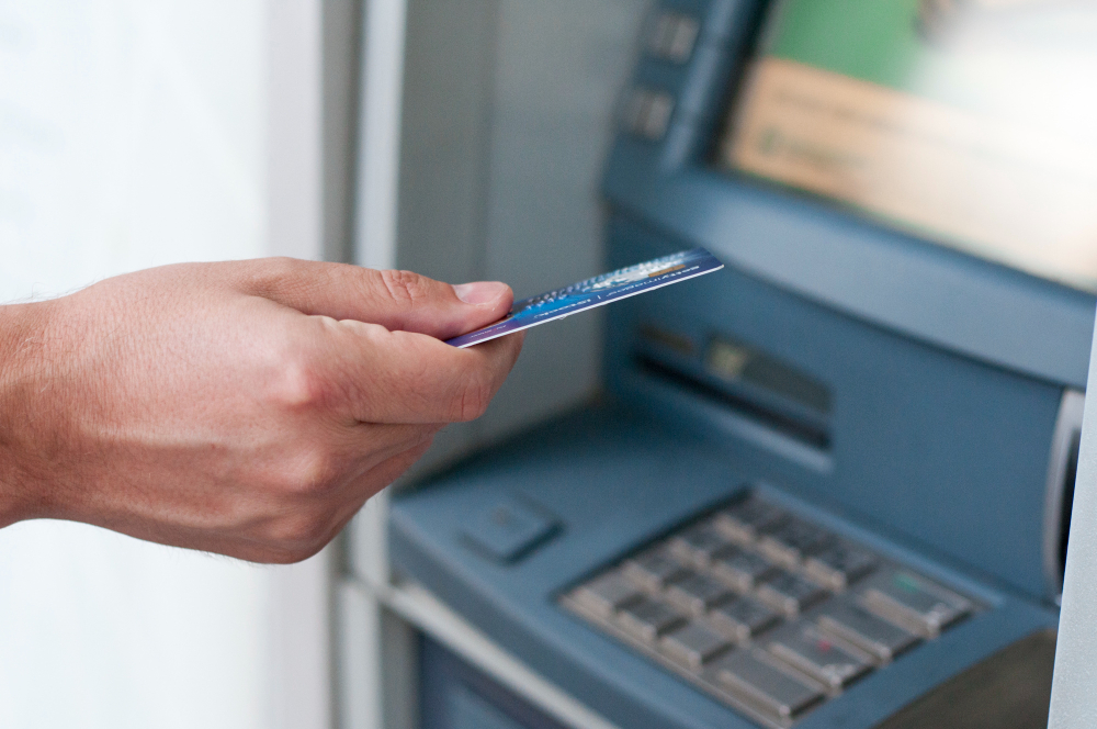 un homme s'appretant à insérer sa carte bancaire dans un distributeur de billet bancaire
