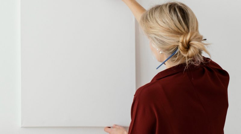 une femme accrochant un tableau blanc