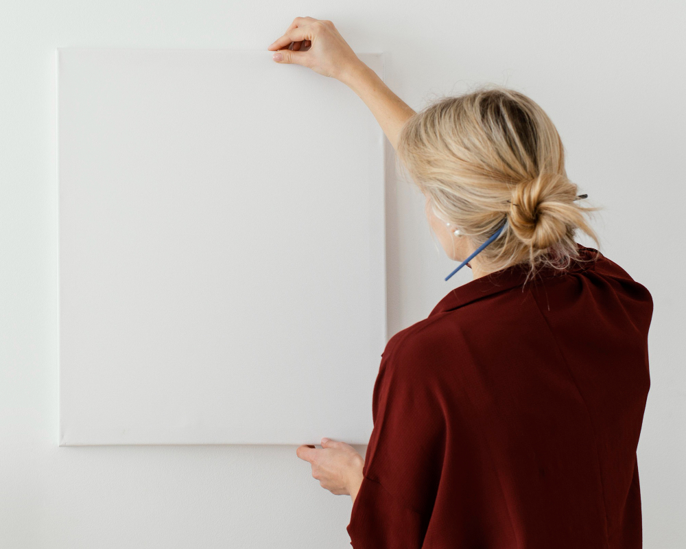 une femme accrochant un tableau blanc