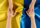 deux personnes se tenant les mains au dessus du drapeau de l'Ukraine