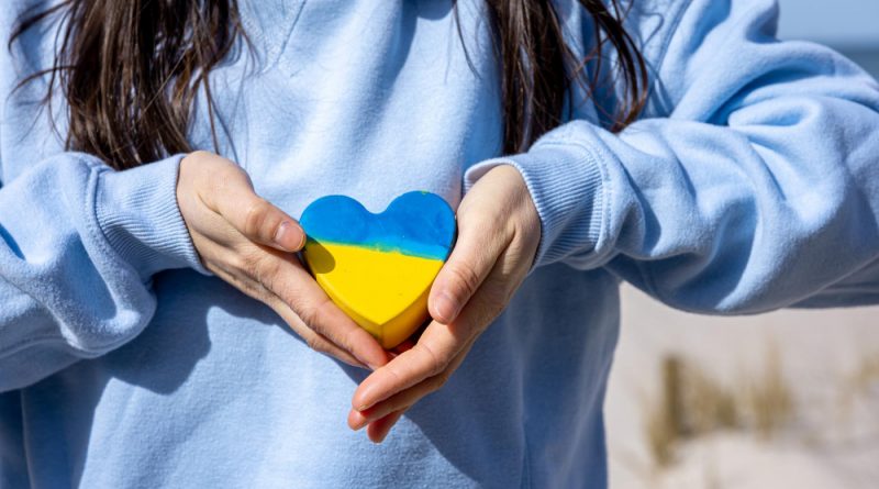 une femme montrant un mini coeur aux couleurs de l'Ukraine