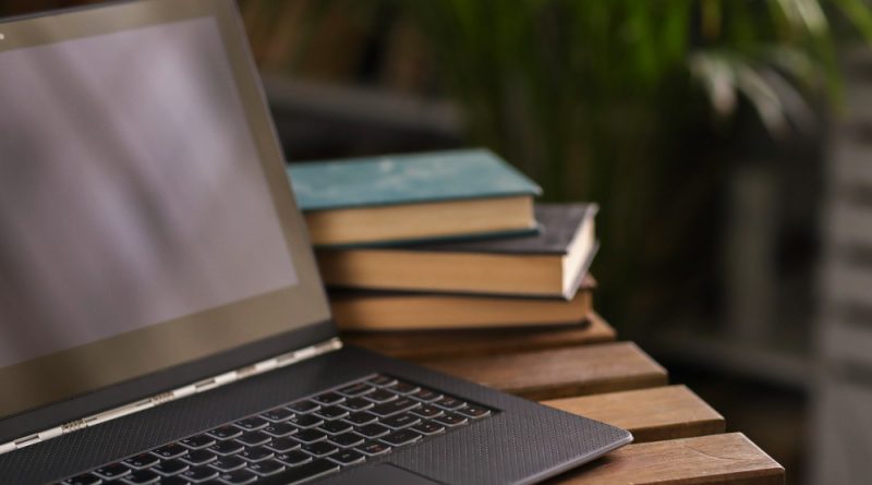 ordinateur près de livres sur une table en bois